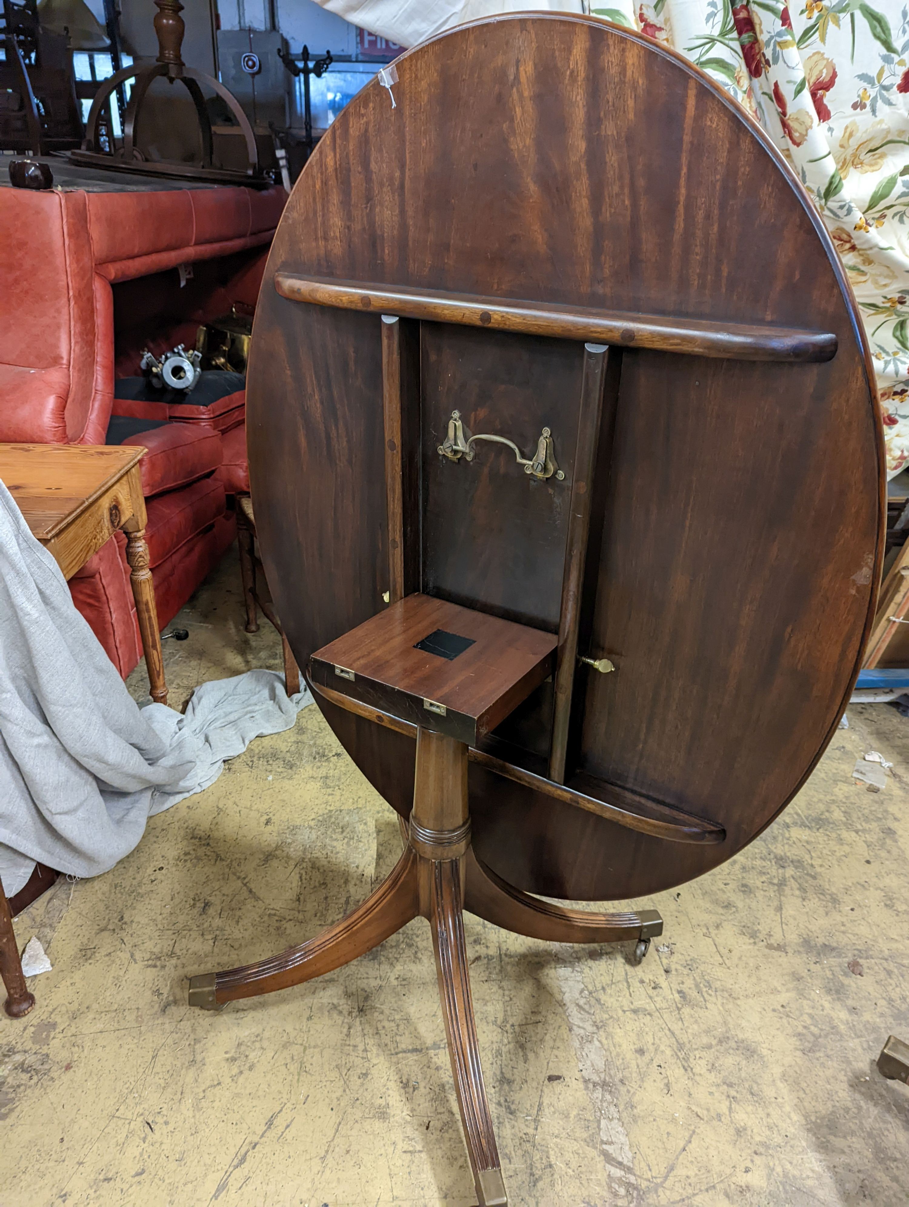 Attributed to William Tillman. A reproduction George III style oval mahogany pedestal tilt top dining table, width 105cm, length 135cm, height 72cm